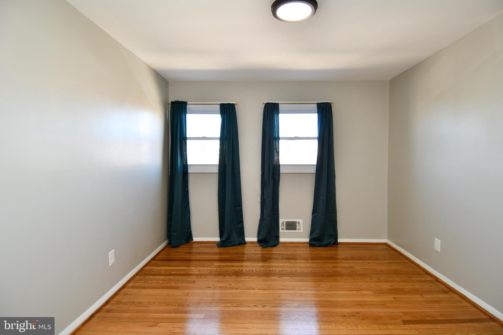 4223 Labyrinth Road Baltimore, MD 21215 - Photo 13 of 22 an empty room with wooden floor and windows