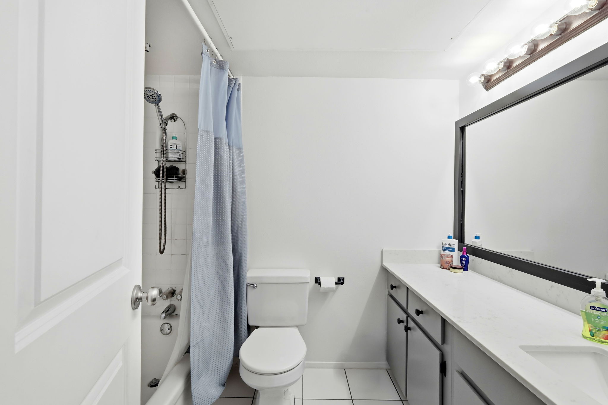 6910 Hart Lane, Unit 912 Austin, TX 78731 - Photo 16 of 36 Bathroom featuring a white bathtub, a toilet, a vanity with a light countertop, dark cabinetry, and a framed mirror with overhead lighting