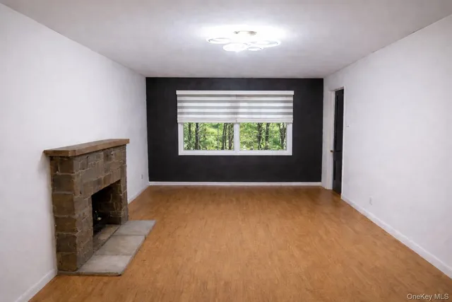 a view of an empty room with a window and fireplace