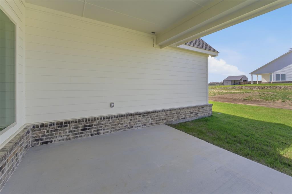 104 Snowy Owl Trail Rhome, TX 76078 - Photo 22 of 27 Covered concrete patio with white horizontal siding and a brick skirting