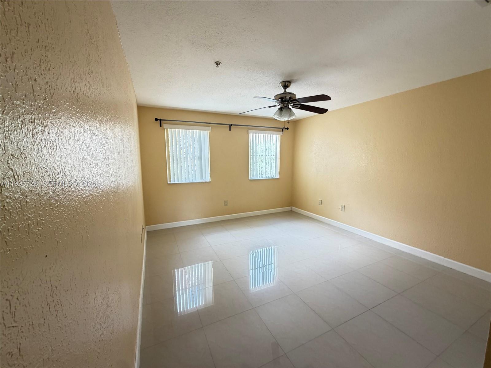7080 Northwest 177th Street, Unit 20913 Hialeah, FL 33015 - Photo 14 of 15 an empty room with windows and ceiling fan