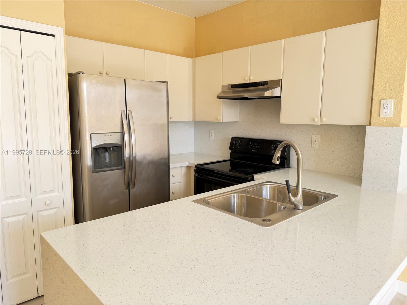 7080 Northwest 177th Street, Unit 20913 Hialeah, FL 33015 - Photo 3 of 15 a kitchen with stainless steel appliances granite countertop a refrigerator a sink a stove and white cabinets