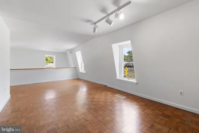 a view of an empty room with window and wooden floor