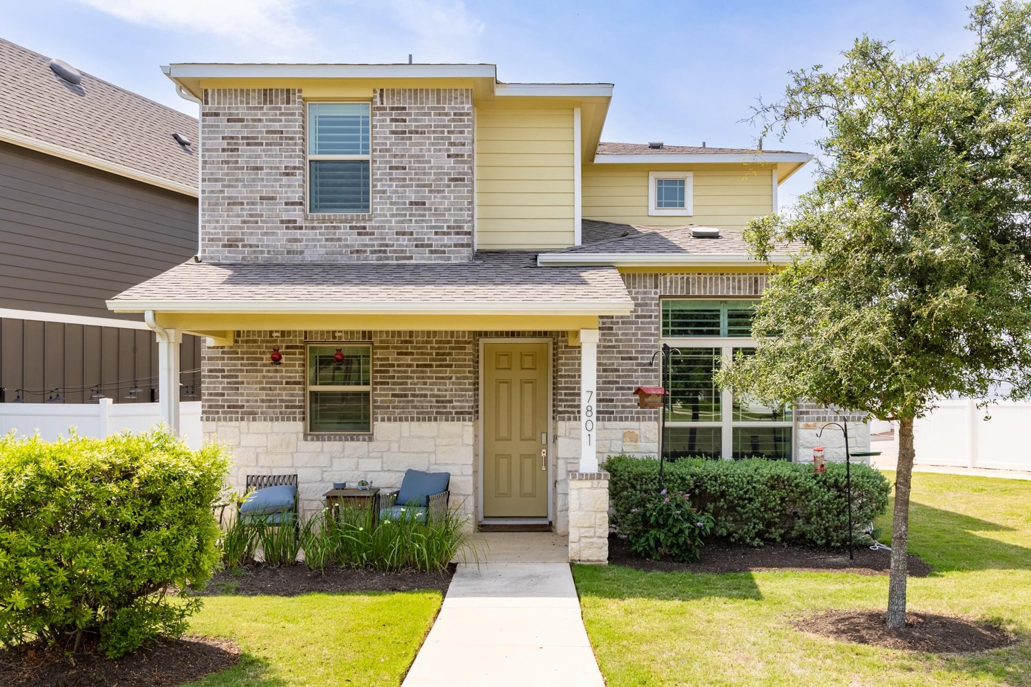 A welcoming front entry is framed by lush landscaping and a cozy porch.
