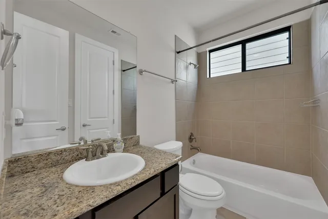 a bathroom with a granite countertop sink toilet a mirror and shower