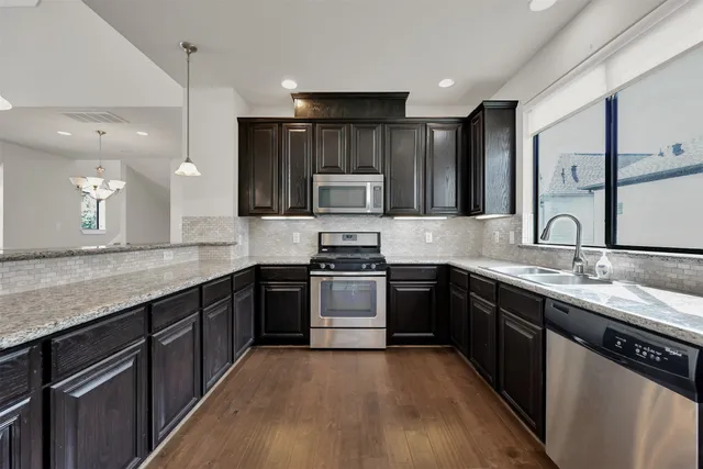 a kitchen with stainless steel appliances granite countertop wooden cabinets stove top oven and sink