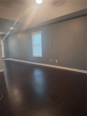 an empty room with wooden floor and windows with curtains