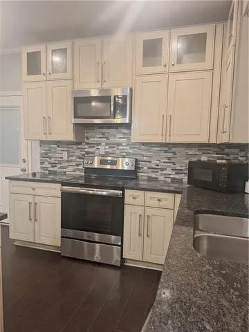 a kitchen with granite countertop white cabinets and stainless steel appliances