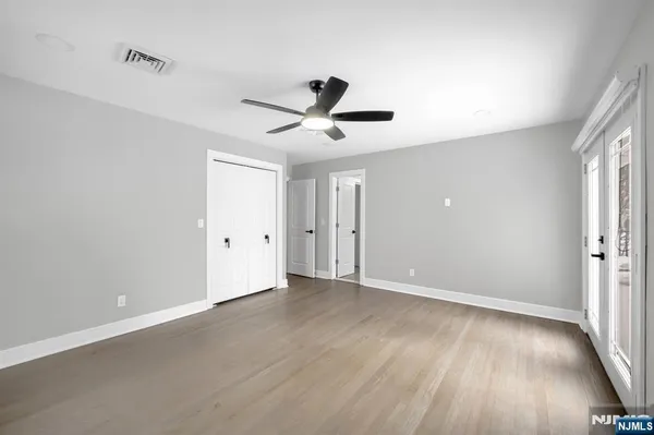 an empty room with wooden floor and ceiling fan
