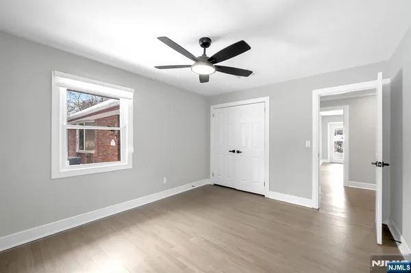 a view of an empty room with window and wooden floor