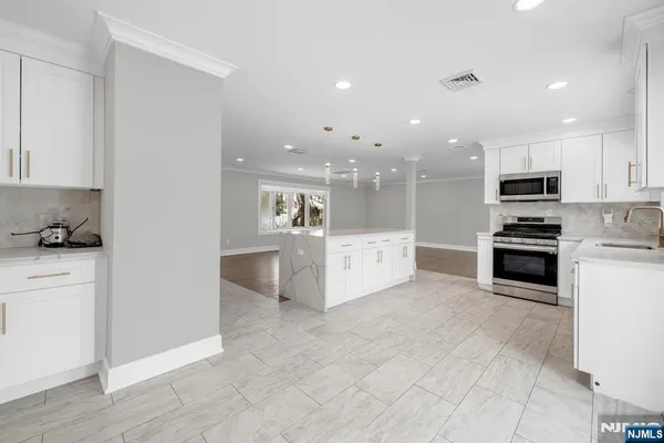 a large white kitchen with kitchen island a sink a stove and a refrigerator