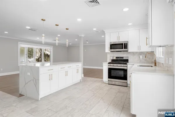 a kitchen with stainless steel appliances kitchen island granite countertop a stove top oven a sink a counter top space and cabinets
