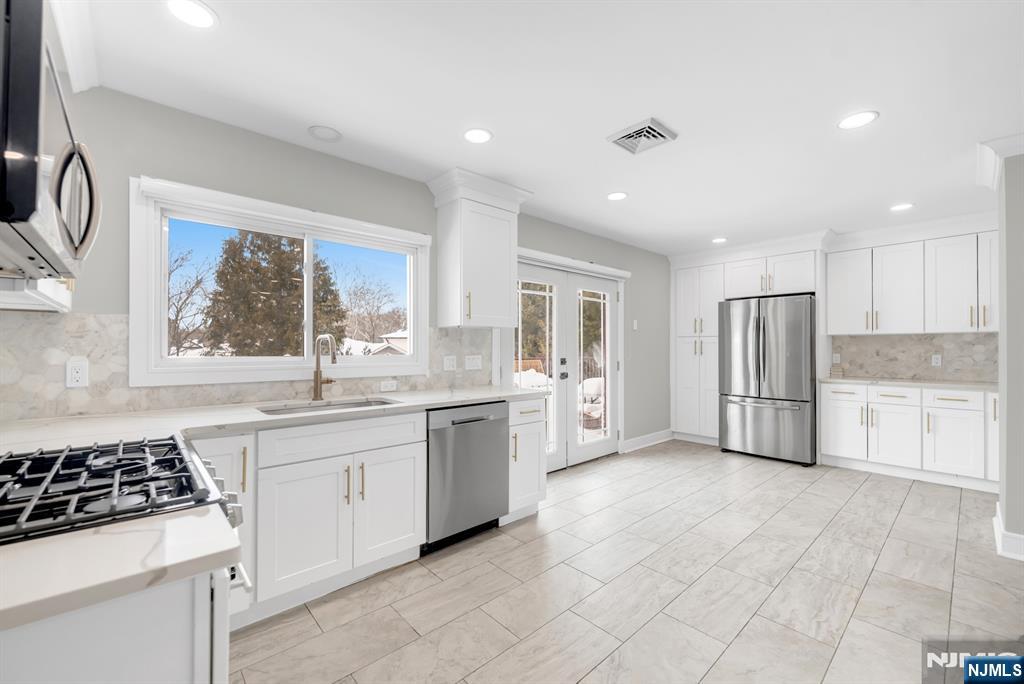 475 Cedar Lane Paramus, NJ 07652 - Photo 9 of 31 a large kitchen with a stove a sink dishwasher a refrigerator and white cabinets with wooden floor