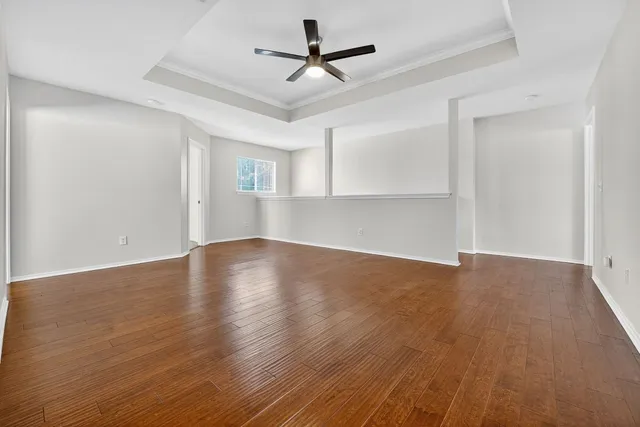 a view of empty room with wooden floor and ceiling fan