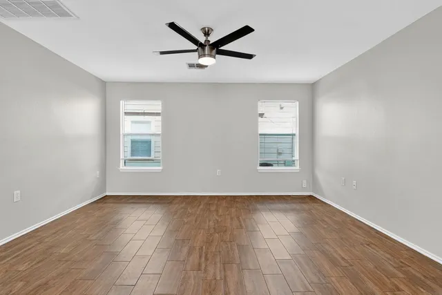 a view of empty room with wooden floor and ceiling fan