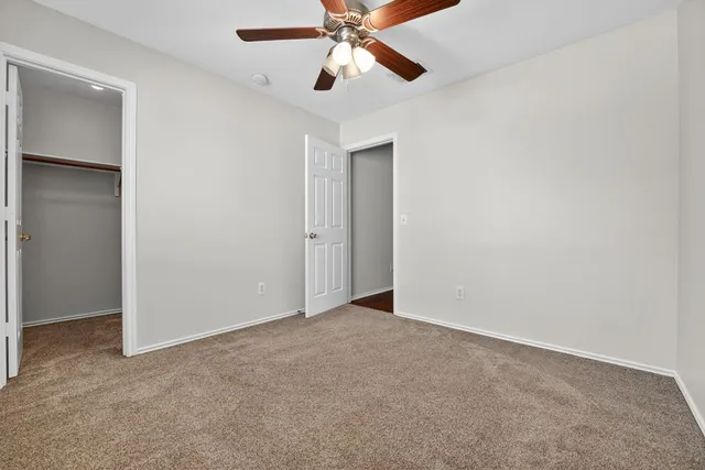 an empty room with closet and a chandelier fan