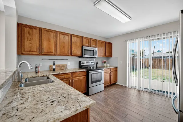 a kitchen with stainless steel appliances granite countertop a stove top oven a sink dishwasher a refrigerator and cabinets with wooden floor