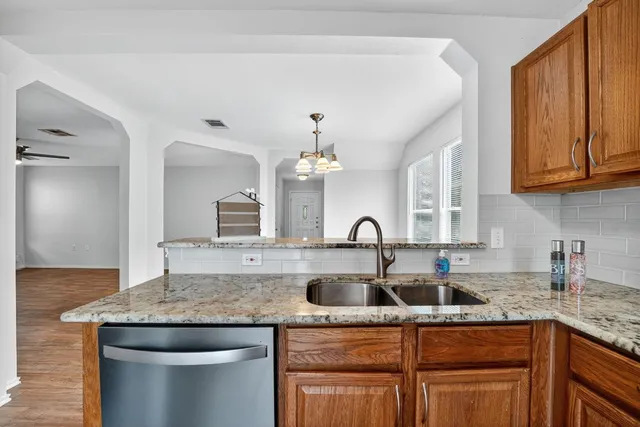 a kitchen with stainless steel appliances granite countertop a sink dishwasher and cabinets with wooden floor