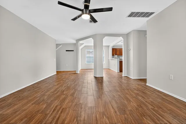 a view of empty room with wooden floor and ceiling fan