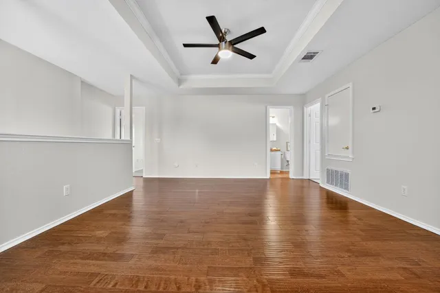 a view of empty room with wooden floor and ceiling fan