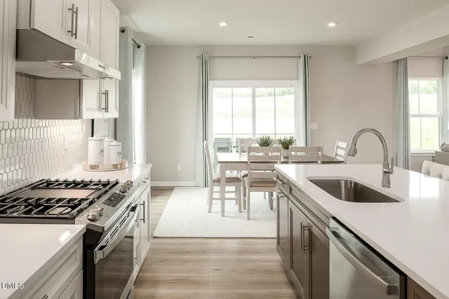 a kitchen with a dining table chairs and white cabinets
