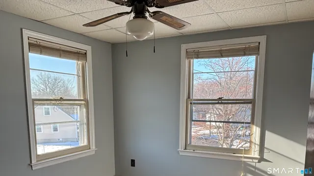 an empty room with windows and ceiling fan