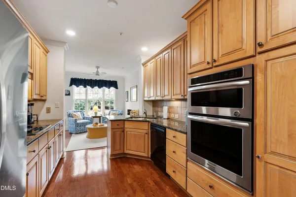 a kitchen with stainless steel appliances granite countertop a stove a sink dishwasher and cabinets with wooden floor