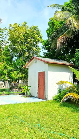 a backyard of a house with plants and large tree