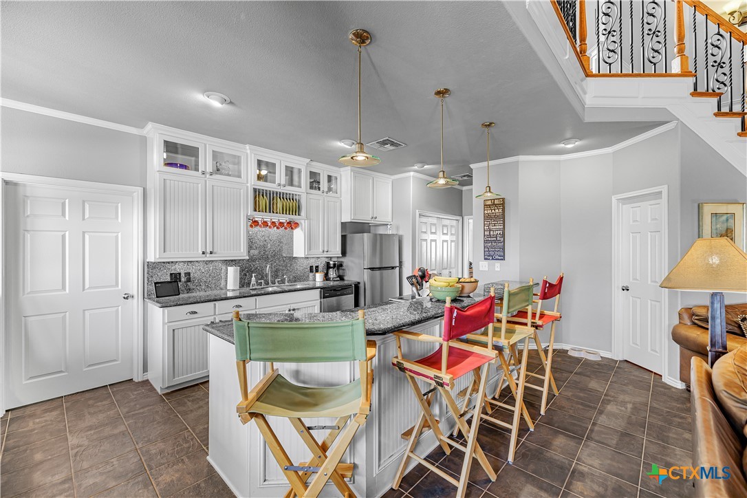 3052 Charco Road Nordheim, TX 78141 - Photo 16 of 43 a kitchen with stainless steel appliances kitchen island granite countertop a table chairs and a refrigerator
