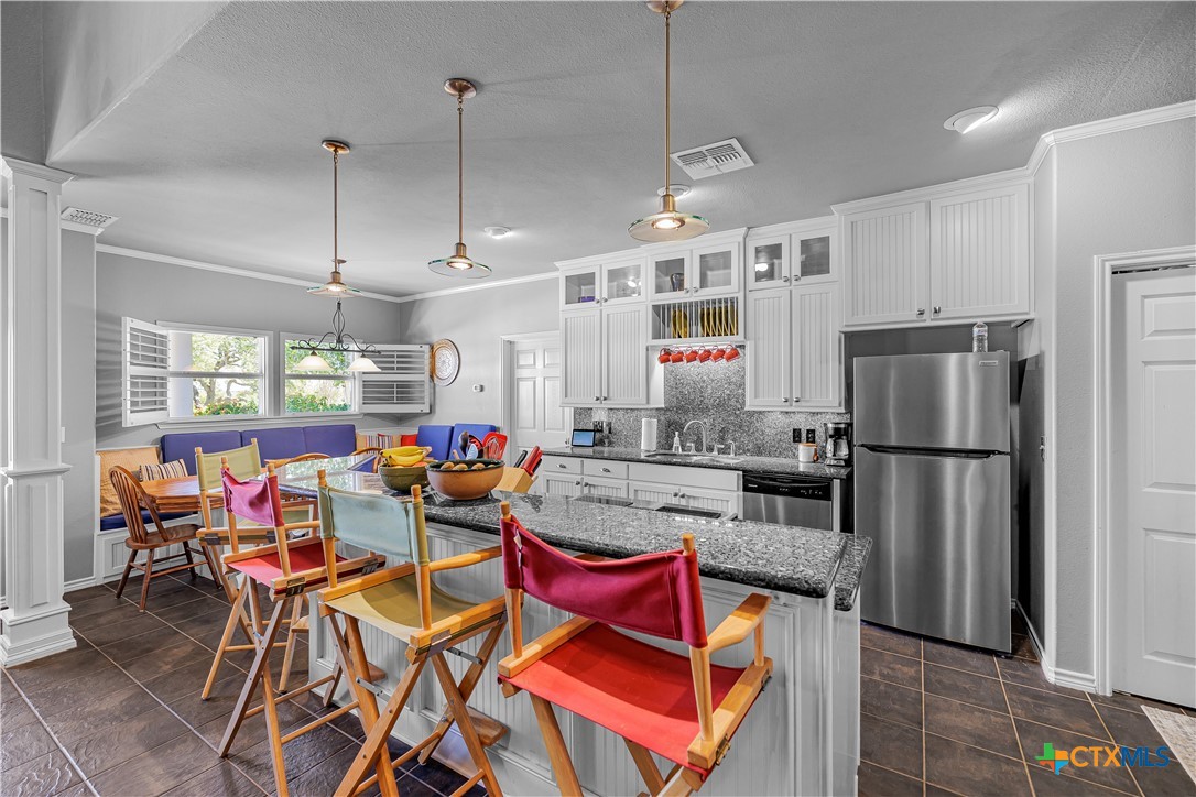 3052 Charco Road Nordheim, TX 78141 - Photo 17 of 43 a kitchen with stainless steel appliances granite countertop a refrigerator a sink dishwasher a dining table and chairs with wooden floor