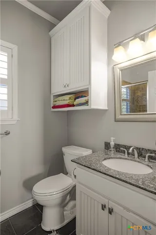 a bathroom with a granite countertop toilet sink and mirror