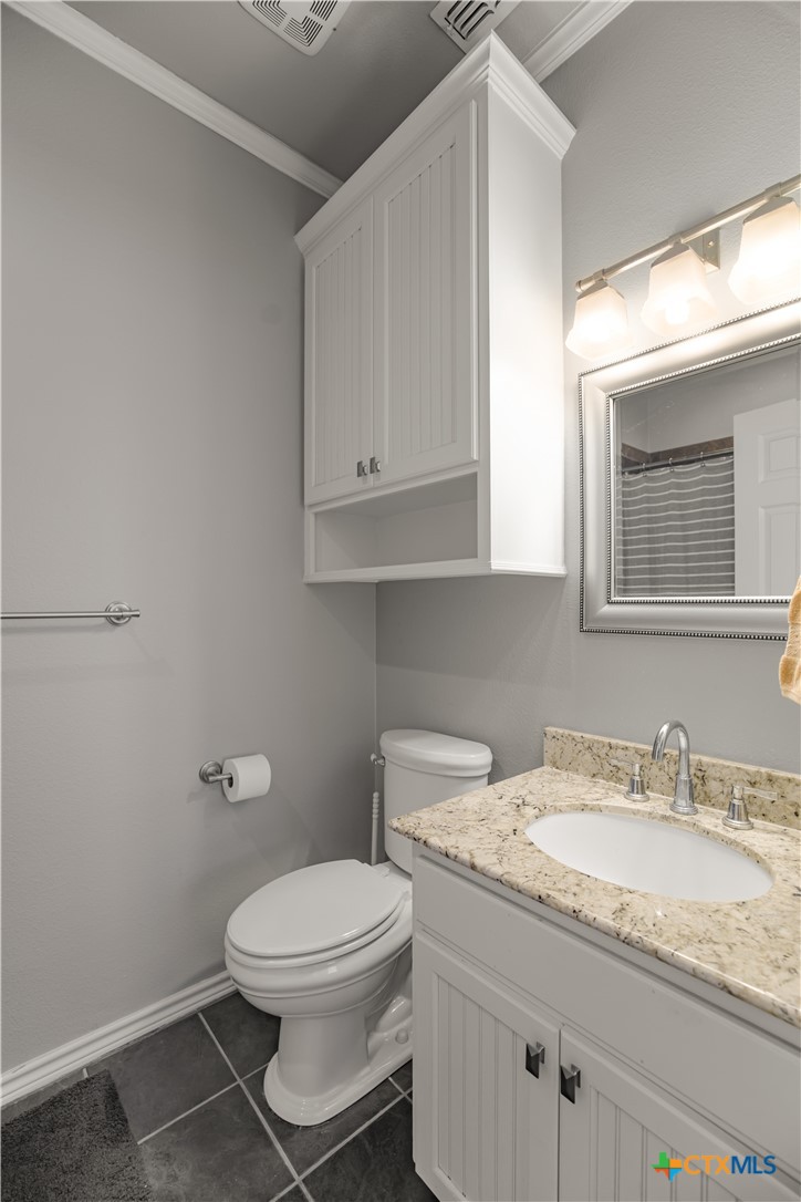 3052 Charco Road Nordheim, TX 78141 - Photo 26 of 43 a bathroom with a granite countertop toilet sink and mirror