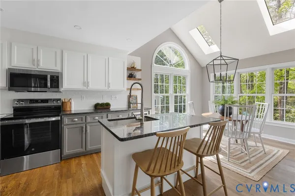 a kitchen with granite countertop a stove a sink a dining table and chairs