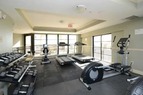 a front view of multi story residential apartment building with yard and parking space