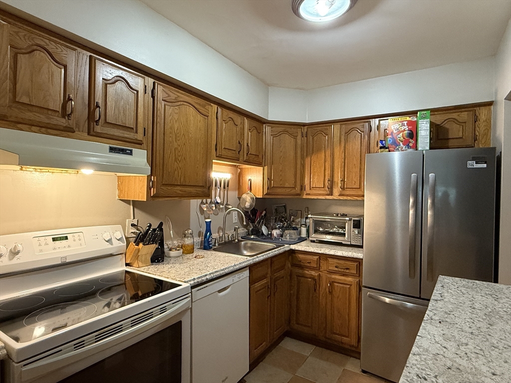 4975 Washington Street, Unit 305 Boston, MA 02132 - Photo 5 of 13 a kitchen with a refrigerator stove and sink