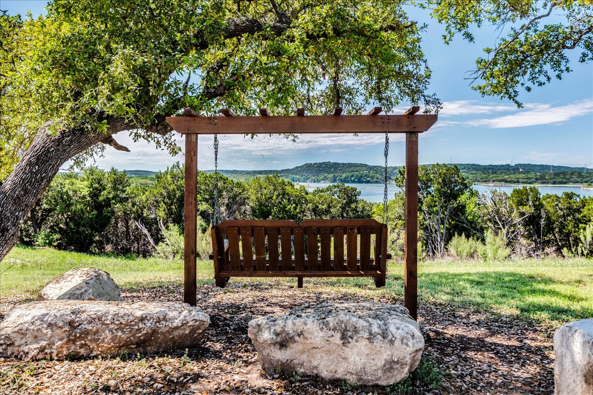 8008 Prairie Rye Drive Lago Vista, TX 78645 - Photo 40 of 40 Outdoor wooden swing with pergola structure set on a natural landscape, offering a broad water and hillside backdrop