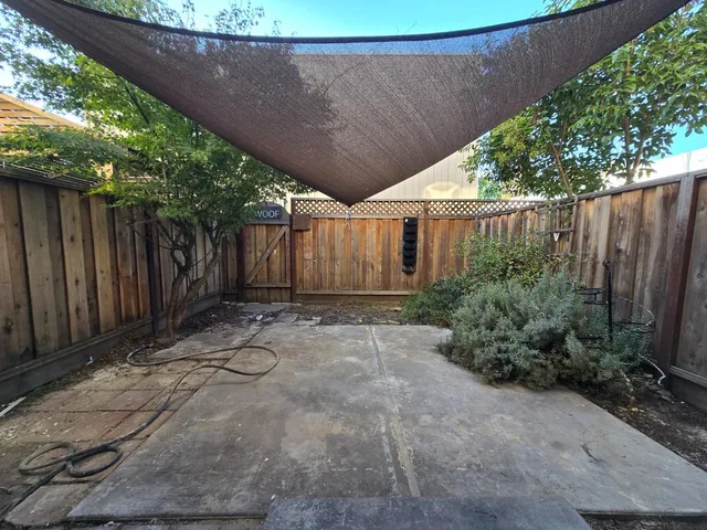 a backyard of a house with plants and trees with wooden fence