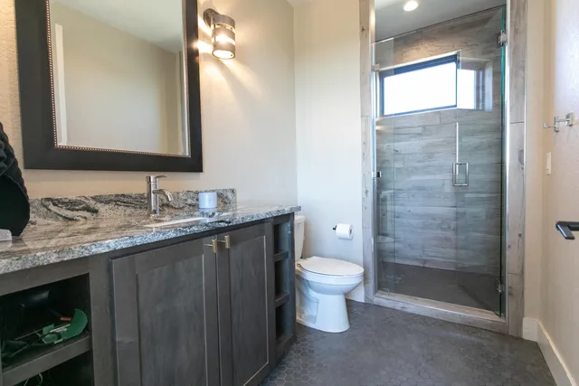 a bathroom with a granite countertop sink toilet a mirror and shower