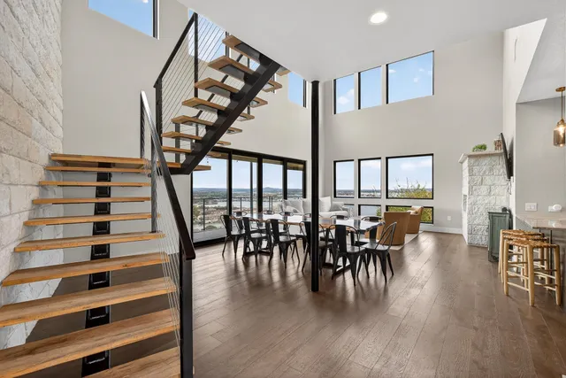 a dining room with furniture floor to ceiling windows and wooden floor