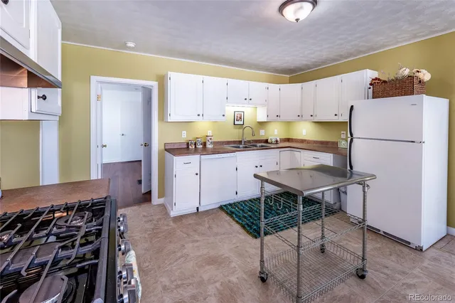 a kitchen with a refrigerator a stove a sink and chairs