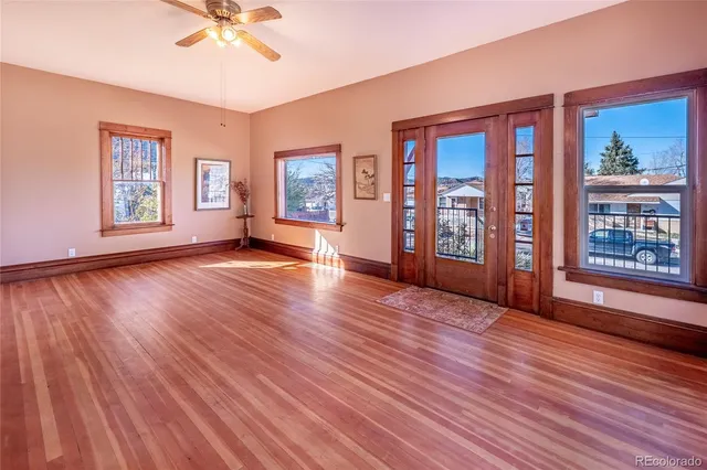 a view of an empty room with wooden floor and a window