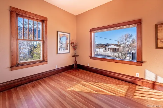 a view of an empty room with window and wooden floor