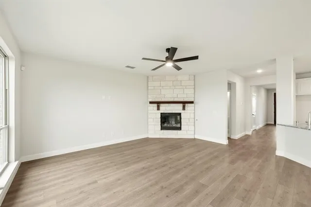 a view of empty room with wooden floor and fireplace