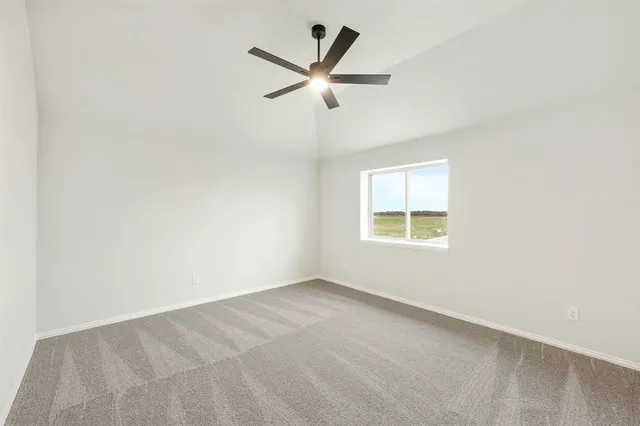 an empty room with ceiling fan and windows