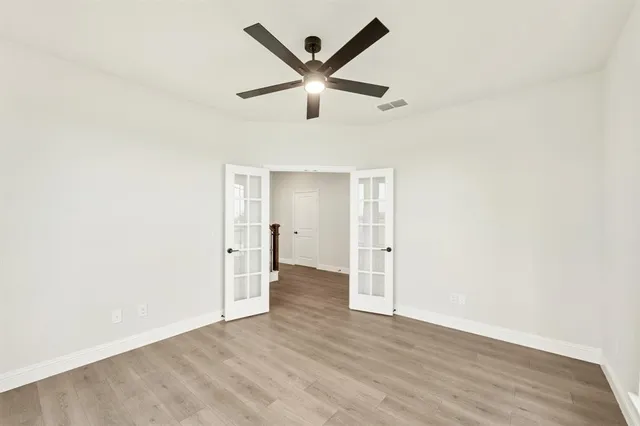 an empty room with wooden floor and ceiling fan