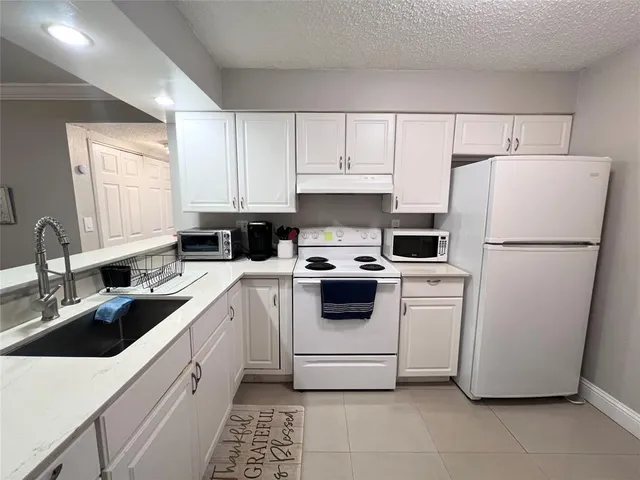 a kitchen with a refrigerator sink and white cabinets