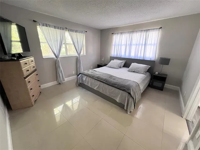 a bedroom with a bed flat screen tv and windows