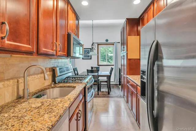 a kitchen with stainless steel appliances granite countertop a sink a stove and refrigerator