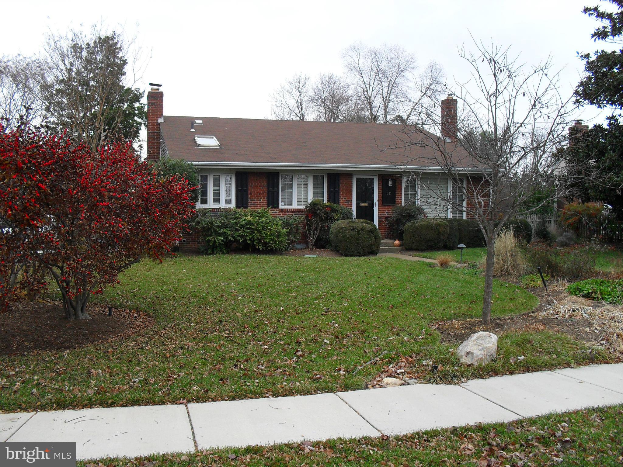 a view of a big yard in front of a brick house with large windows