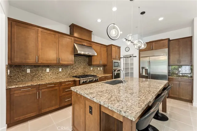 a kitchen with granite countertop stainless steel appliances a stove refrigerator and cabinets